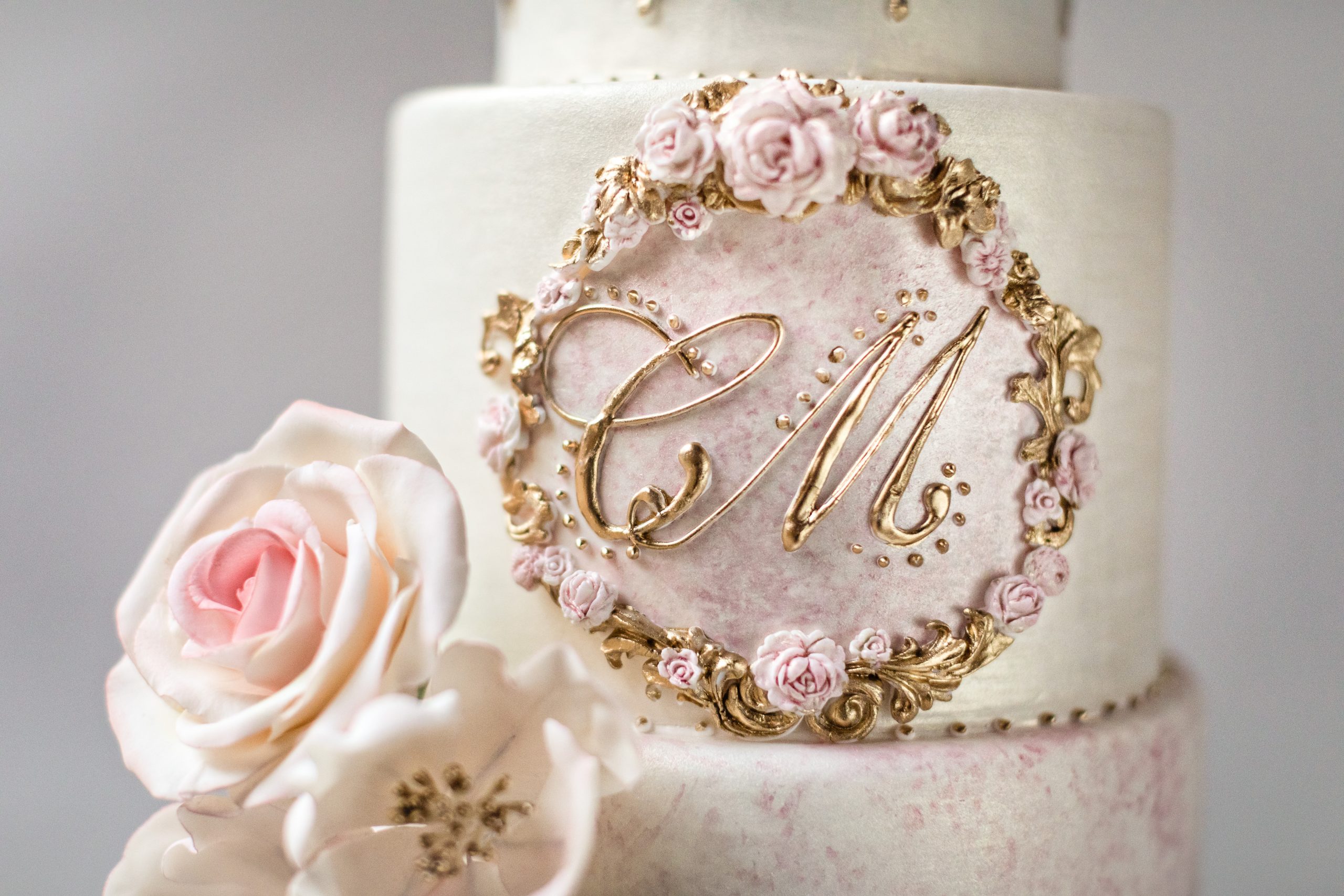 Exquisite wedding cake with custom monogram, gold and pink details and sugar roses. Best Wedding Cakes in Connecticut by Master Sugar Artist Ana Parzych